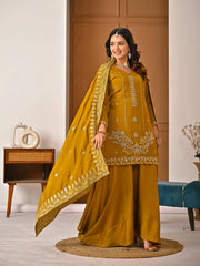 Woman in a mustard yellow traditional outfit with embroidery indoors.