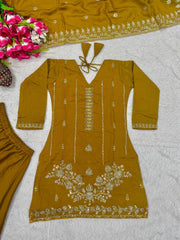 Mustard yellow embroidered outfit with floral patterns on a light gray surface.