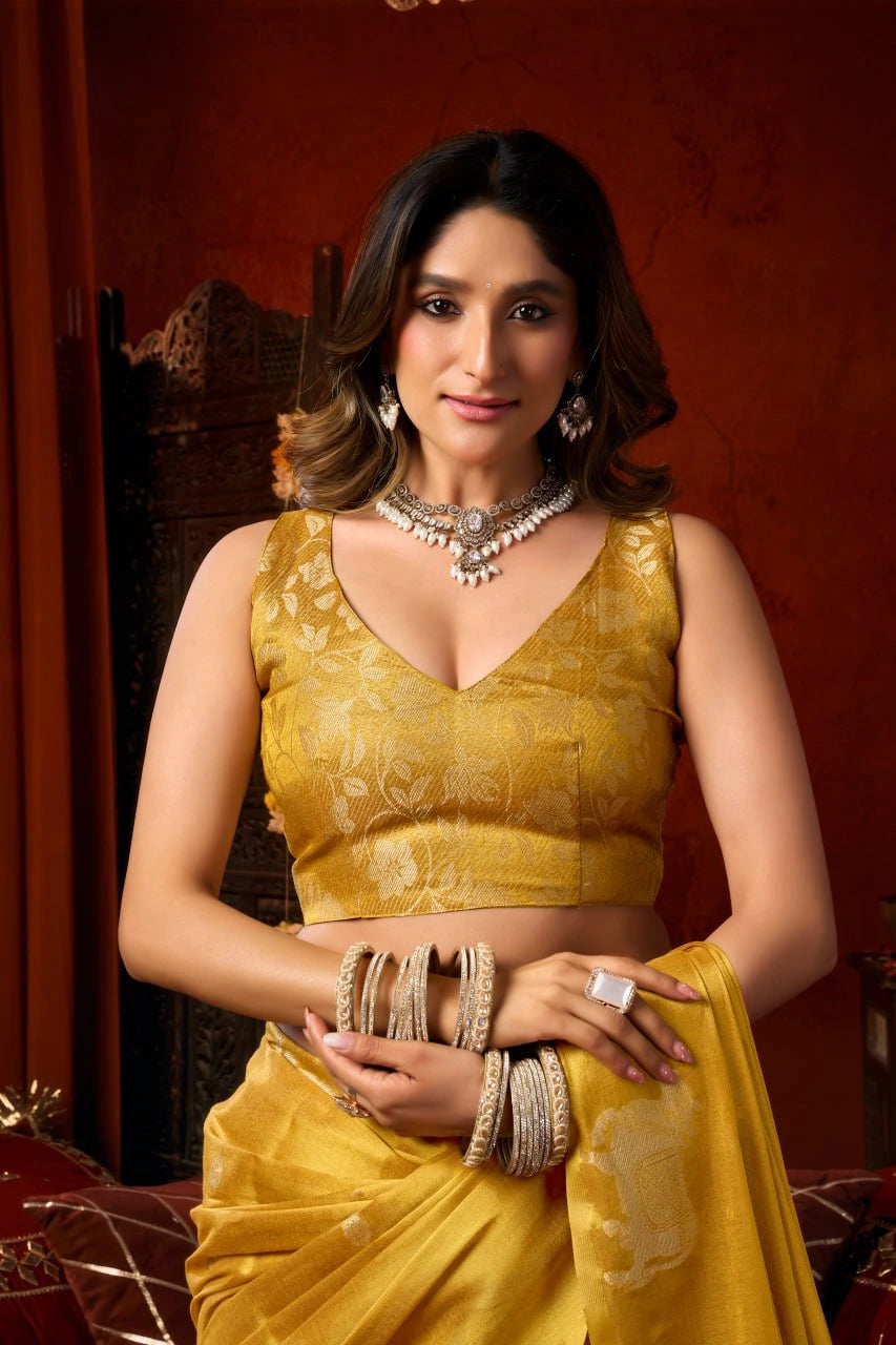 Woman in a yellow saree with jewelry against a red background