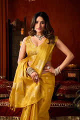 Woman in a yellow saree posing in an ornate room.
