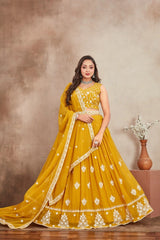 Woman in a yellow embroidered traditional outfit standing against a brown background
