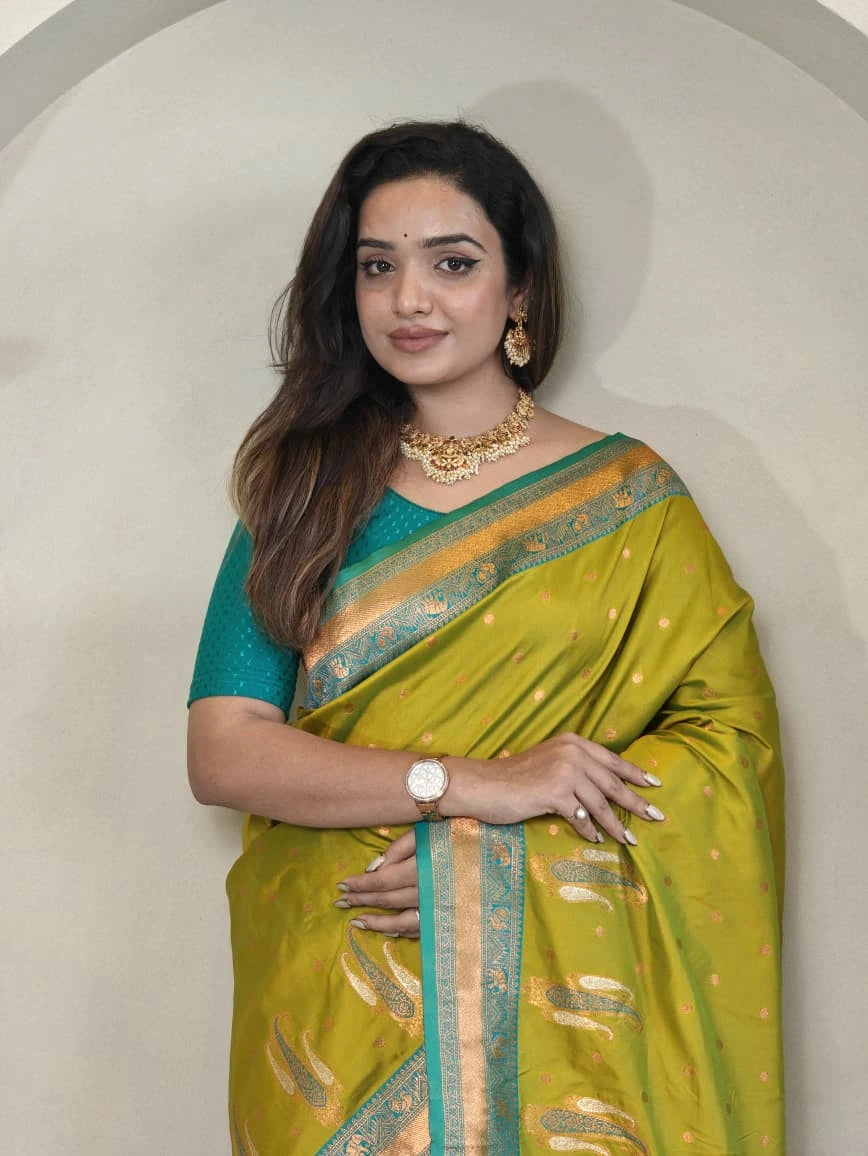 Woman wearing a green saree with a gold border against a plain background