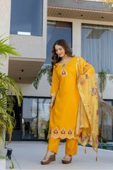 Woman in a yellow traditional outfit standing in front of a modern building.