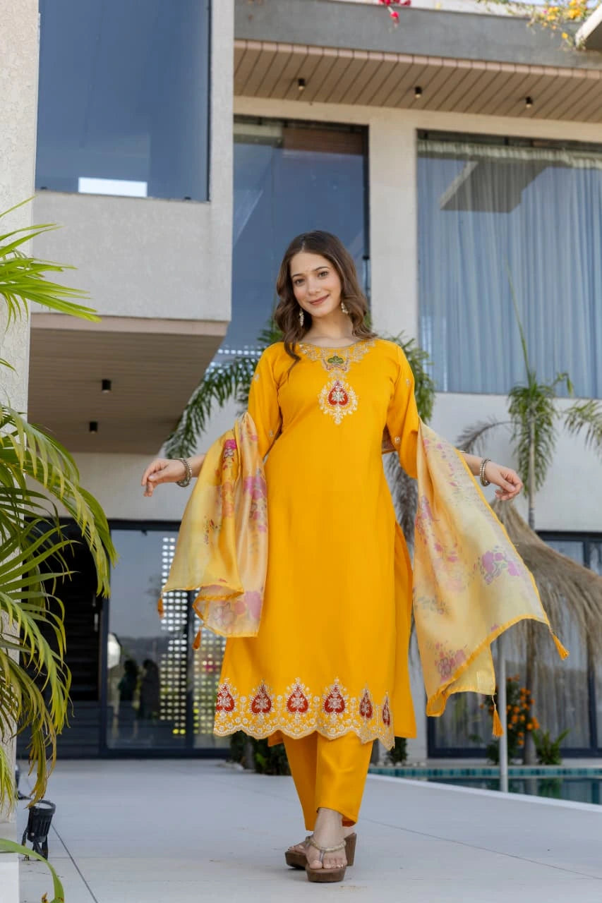 Woman in a yellow traditional outfit standing in front of a modern building.