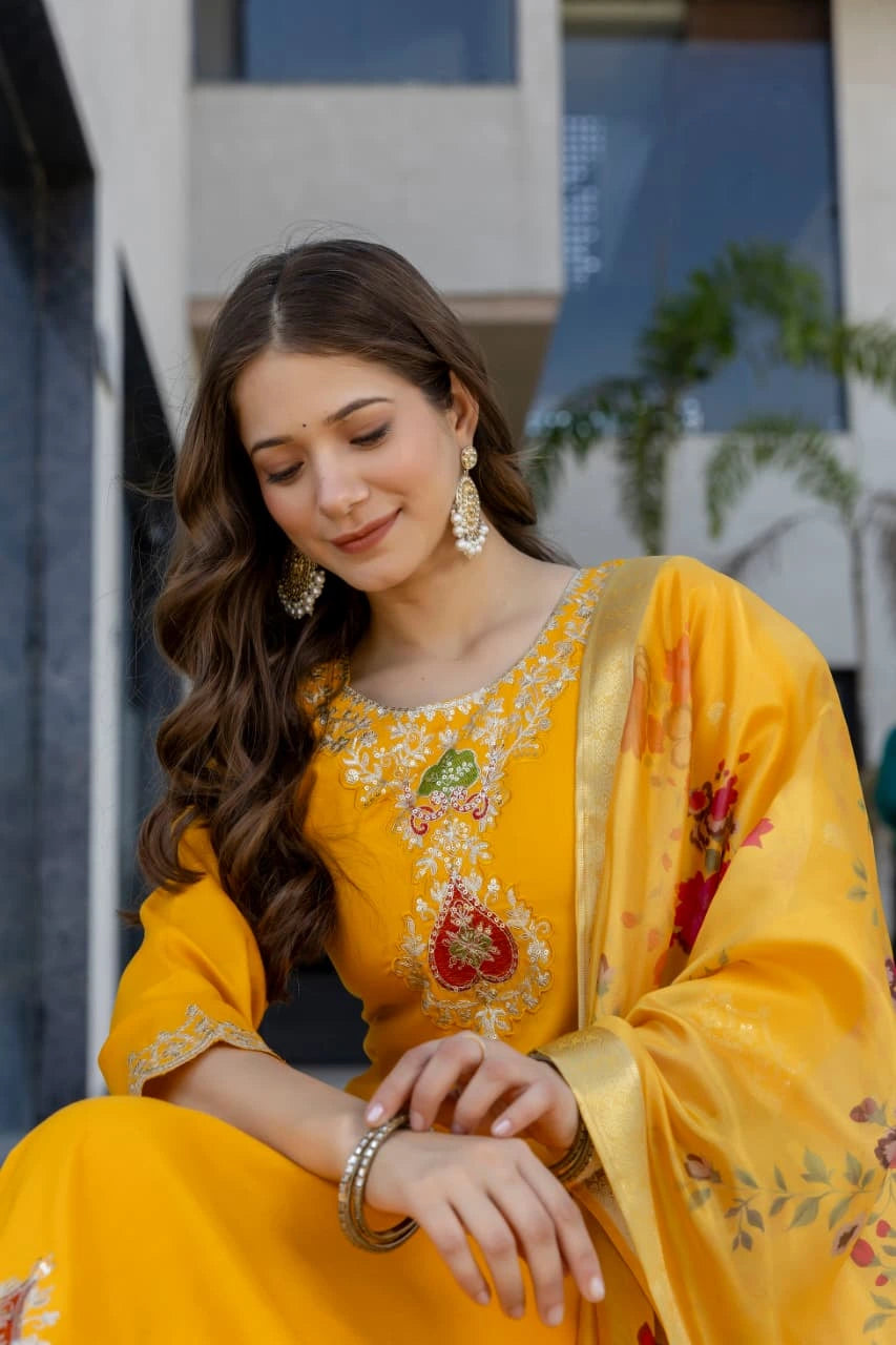 Woman in a yellow embroidered outfit sitting outdoors with a blurred background
