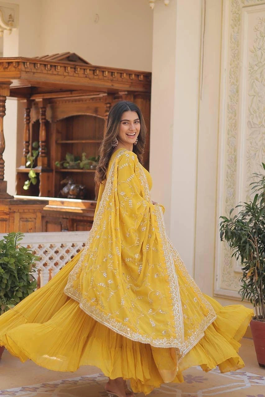Woman in a yellow traditional outfit standing in an elegant room with decorative elements.