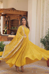 Woman in a yellow traditional outfit standing in an ornate room.