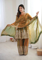 Woman in traditional embroidered outfit with a green dupatta in a bright room.