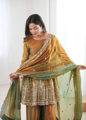 Woman wearing a mustard yellow and green traditional outfit with intricate patterns.