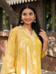 Woman wearing a yellow traditional outfit with a floral pattern, standing outdoors.