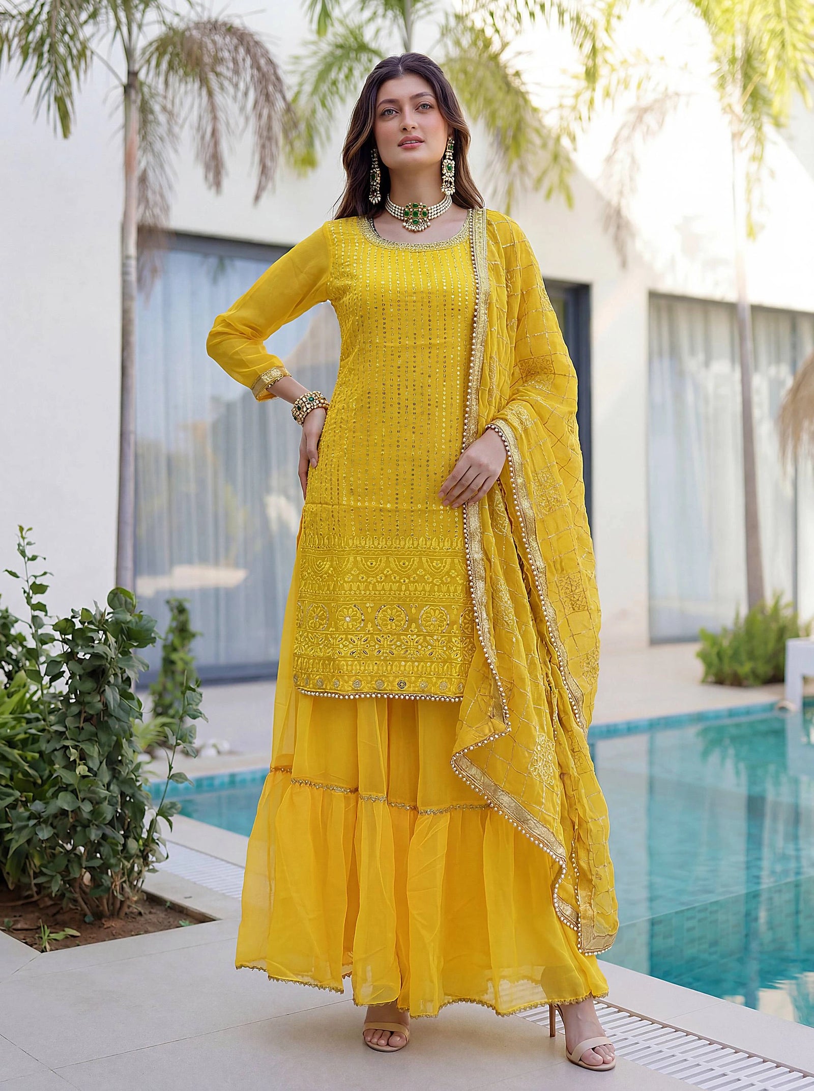 Woman in a yellow traditional outfit standing by a pool