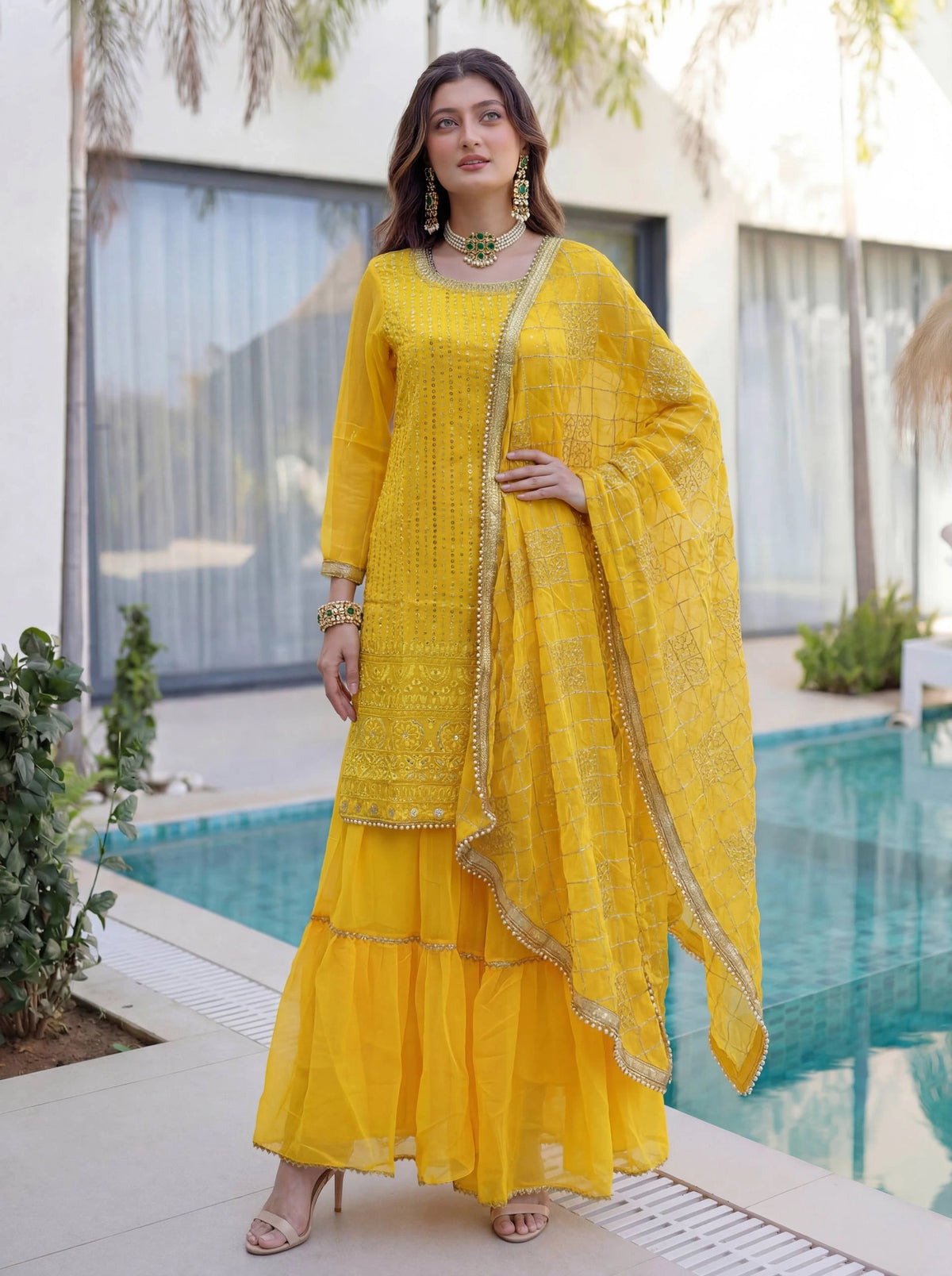 Woman in a yellow traditional outfit standing by a poolside.
