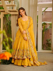 Woman in a yellow traditional outfit with floral patterns standing outdoors.