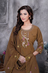 Woman wearing a brown embroidered outfit against a gray background