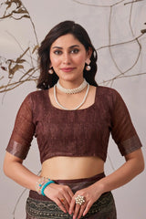 Woman wearing a brown blouse with sheer sleeves against a neutral background