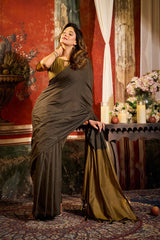 Woman in a dark green saree standing in an ornate room with floral decorations.