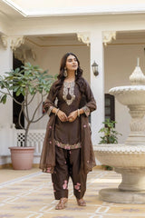 Woman in traditional brown outfit standing in a decorative indoor setting