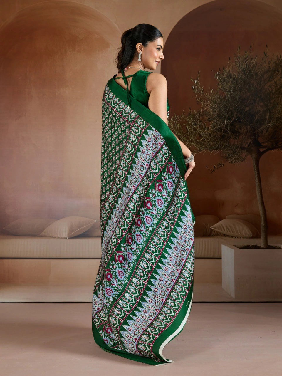 Woman wearing a green saree with a pattern in an indoor setting