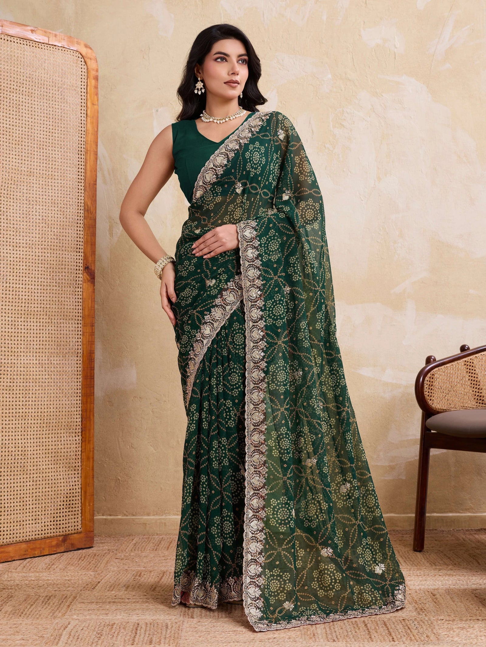 Woman wearing a green saree with intricate patterns in a room setting.