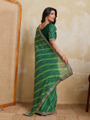 Woman wearing a green saree with a textured wall background