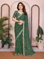 Woman wearing a green saree with floral patterns in a decorative setting with plants.