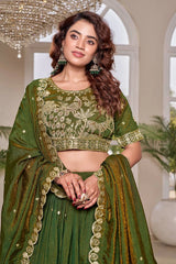Woman wearing a green embroidered traditional outfit with a chandelier in the background