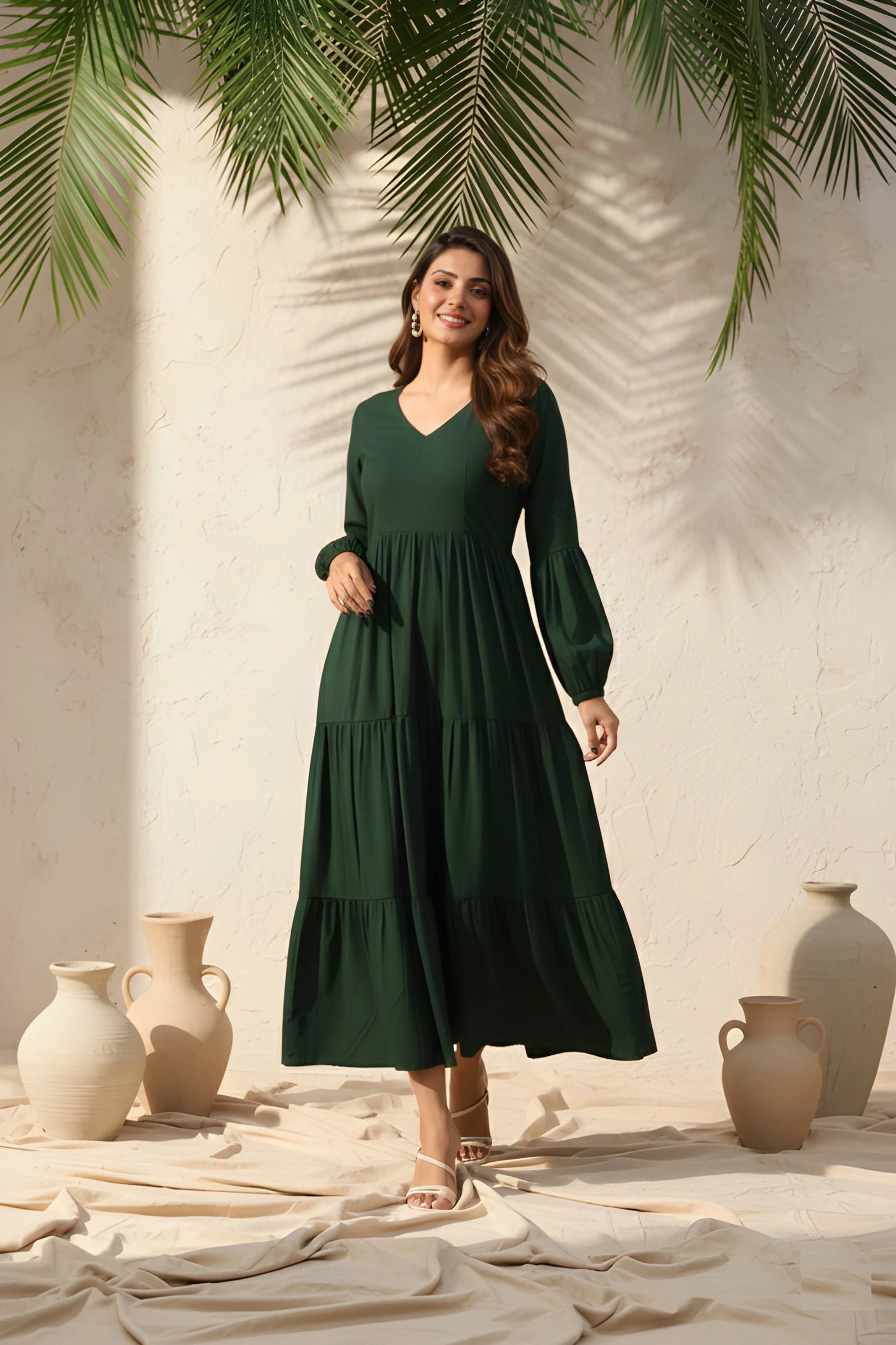 Woman in a green dress standing in front of a neutral wall with decorative vases and plants.