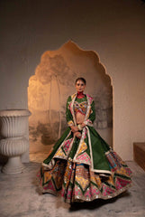 Woman in a traditional outfit standing in front of an ornate wall design.