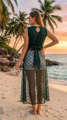 Woman standing on a beach with palm trees and sunset in the background