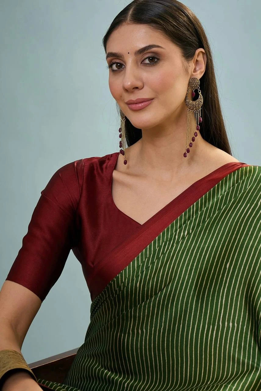 Woman wearing a green saree with a red blouse against a light blue background
