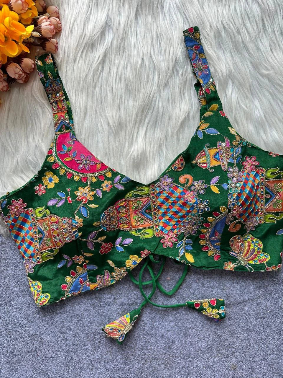 Colorful patterned top on a textured surface with flowers in the background