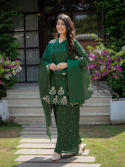 Woman in a green traditional outfit standing outdoors with flowers and steps in the background