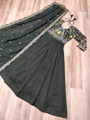 Dark green saree with embroidered blouse on a wooden floor
