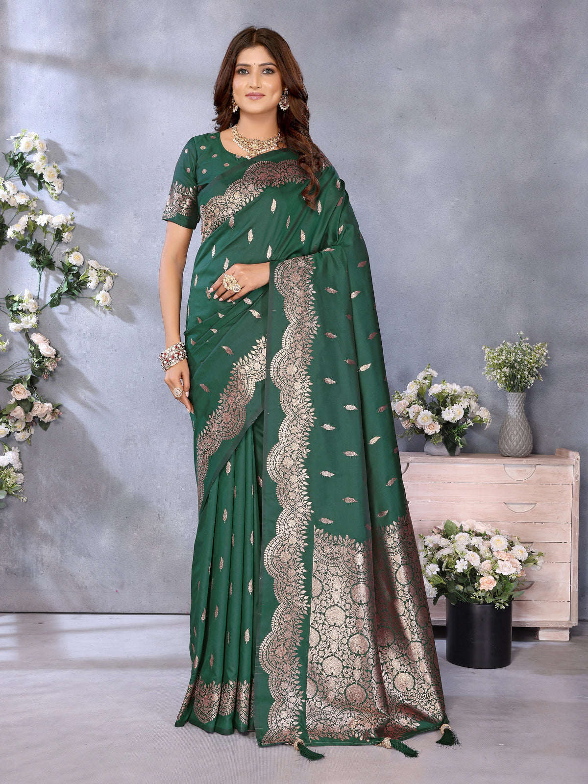 Woman wearing a green saree with silver border against a gray background