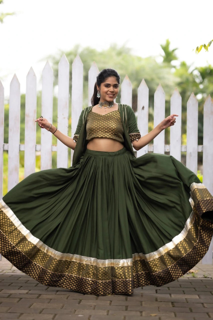 Woman in a green traditional outfit with a white picket fence and greenery in the background