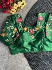 Green embroidered blouse with floral patterns on a textured surface.