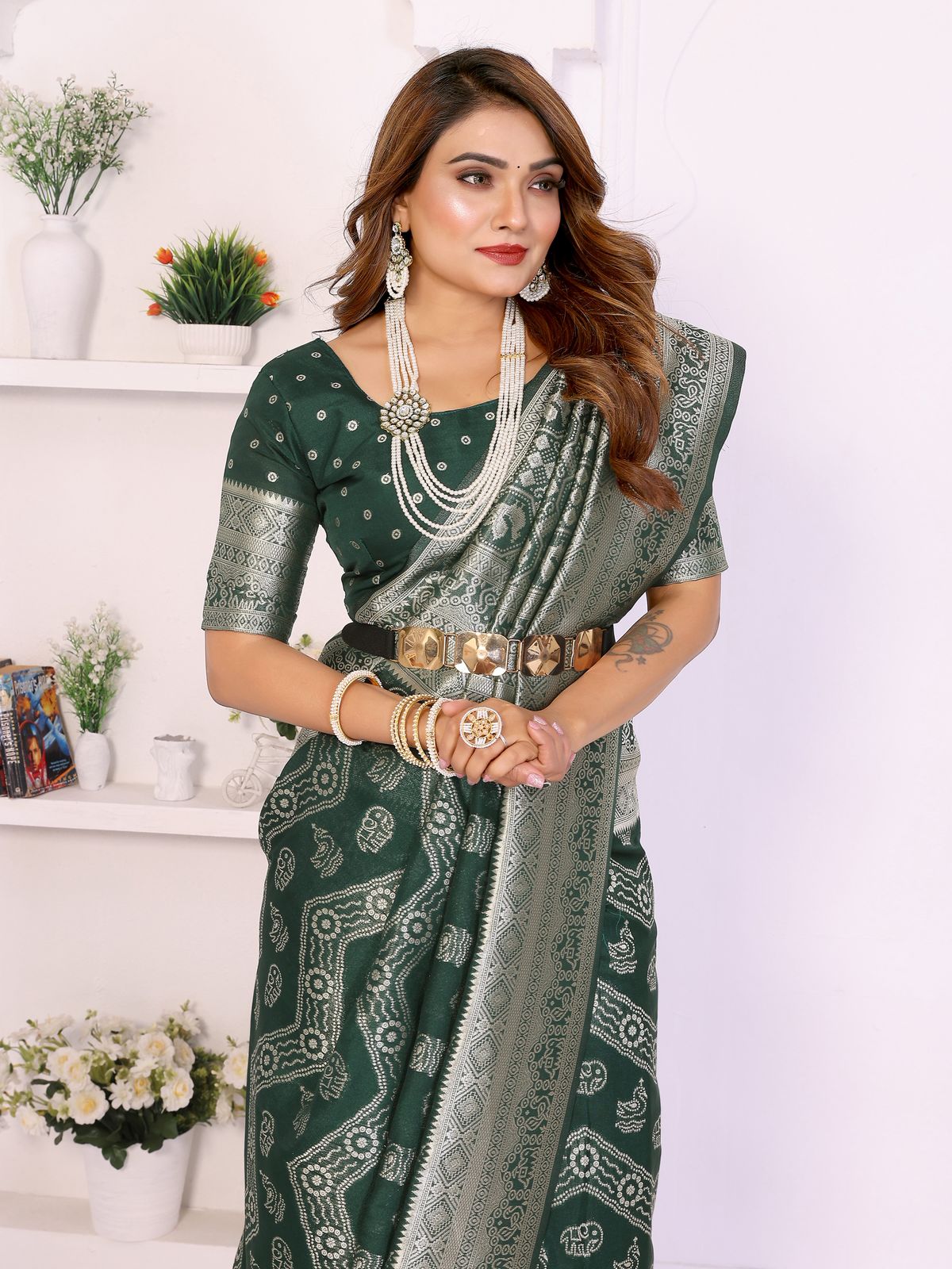 Woman wearing a green saree with silver patterns against a white background