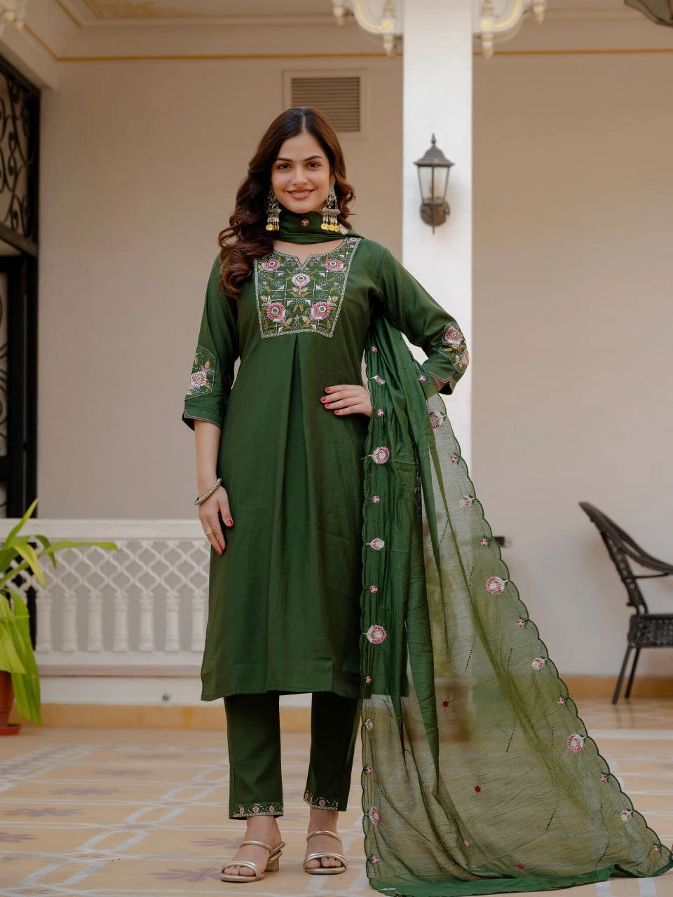 Woman wearing a green traditional outfit with embroidery in an indoor setting