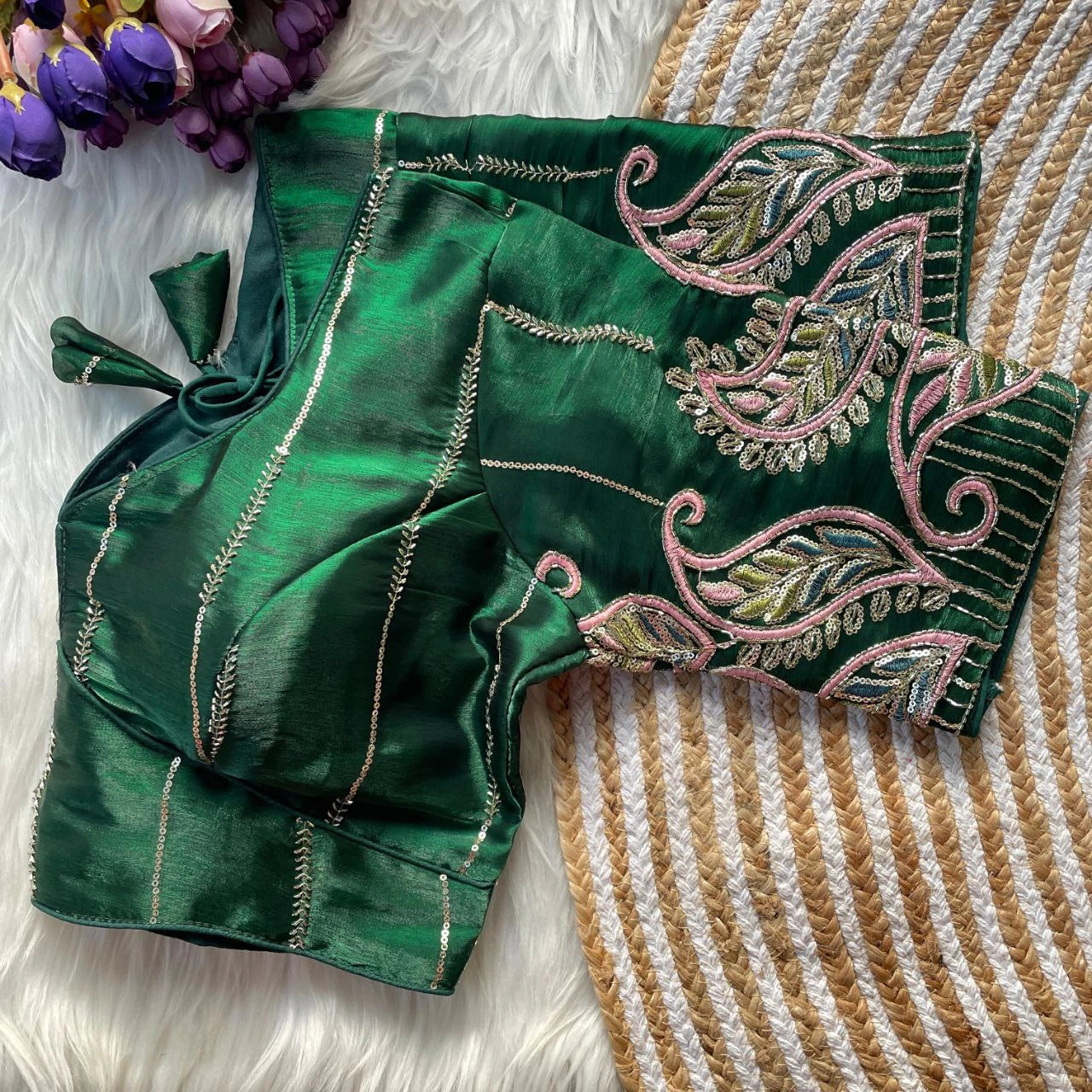 Green embroidered blouse on a textured surface with flowers in the background