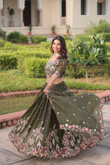 Woman in an embroidered traditional outfit standing outdoors with greenery in the background