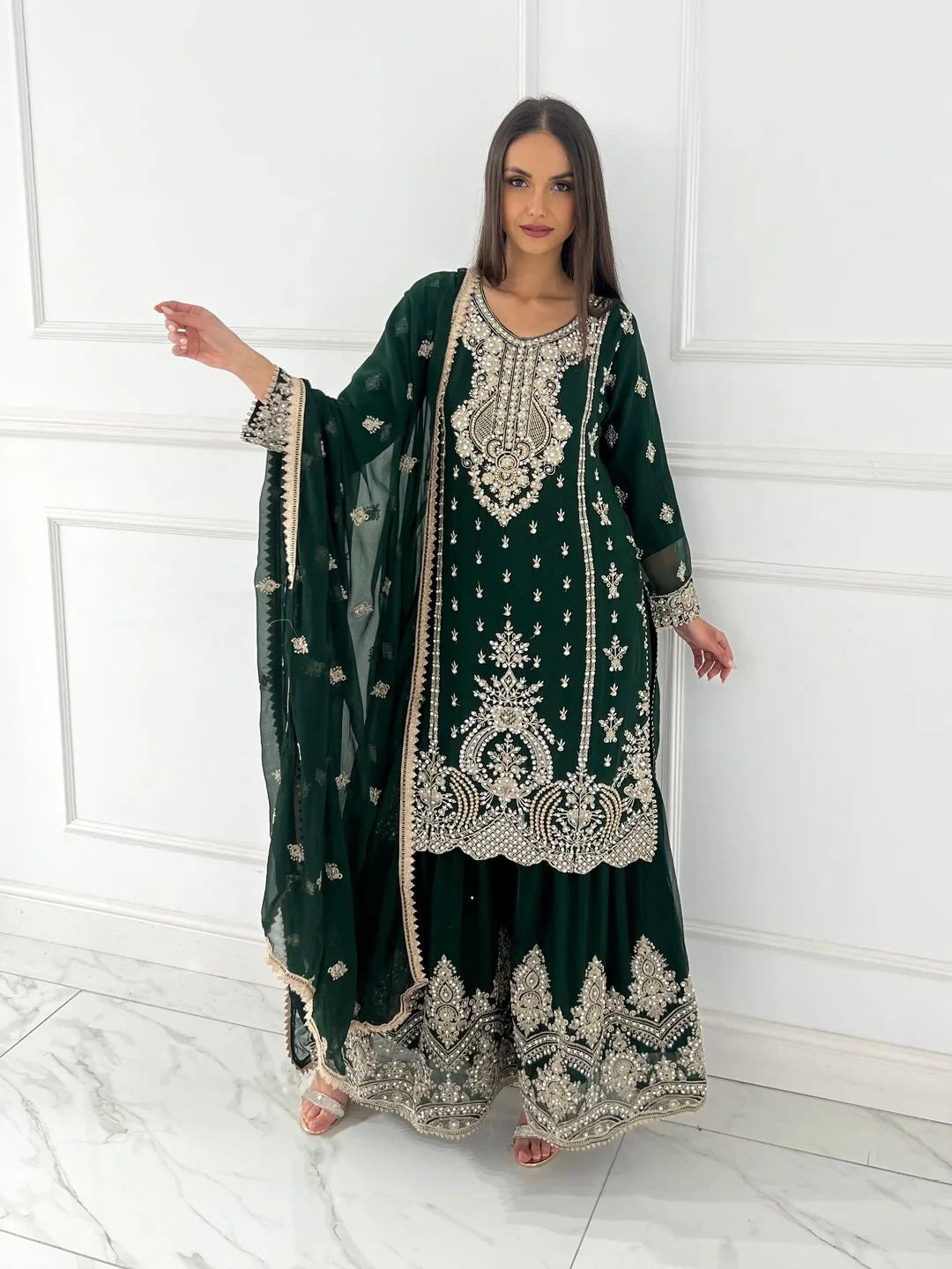 Woman wearing a green embroidered traditional outfit with a white background
