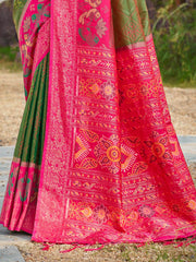 Traditional pink and green saree with intricate patterns on a natural background