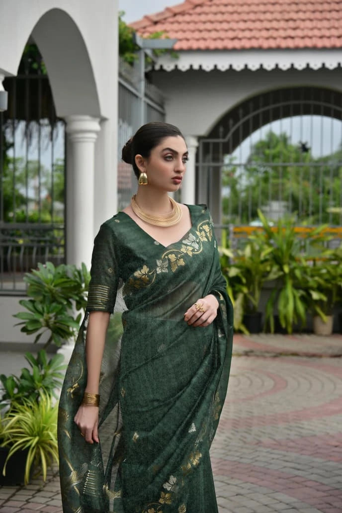 Woman in a green saree with floral patterns standing outdoors.