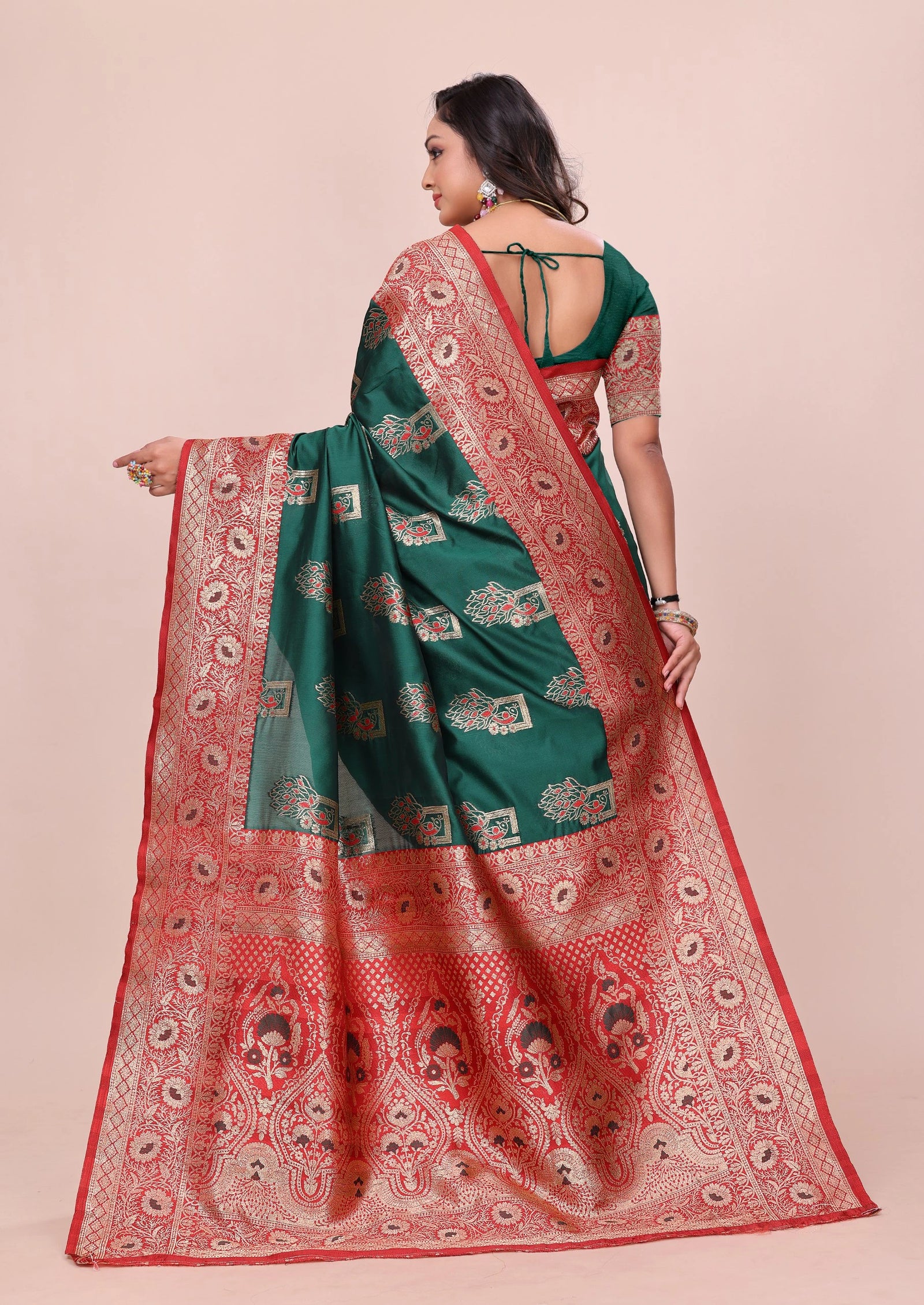 Woman wearing a green and red saree with a pattern on a beige background