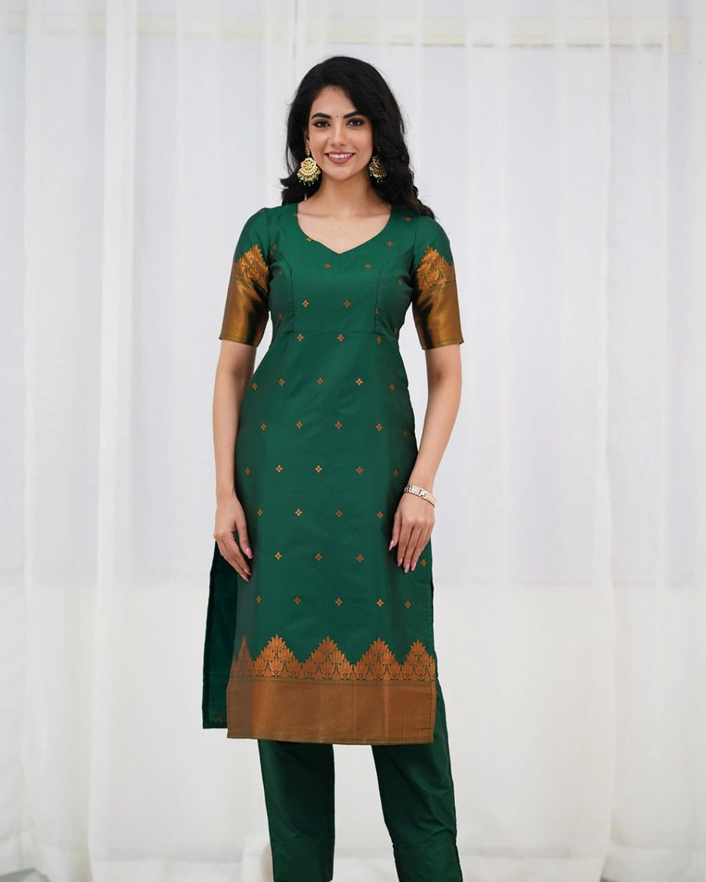 Woman wearing a green traditional outfit with gold patterns against a white background