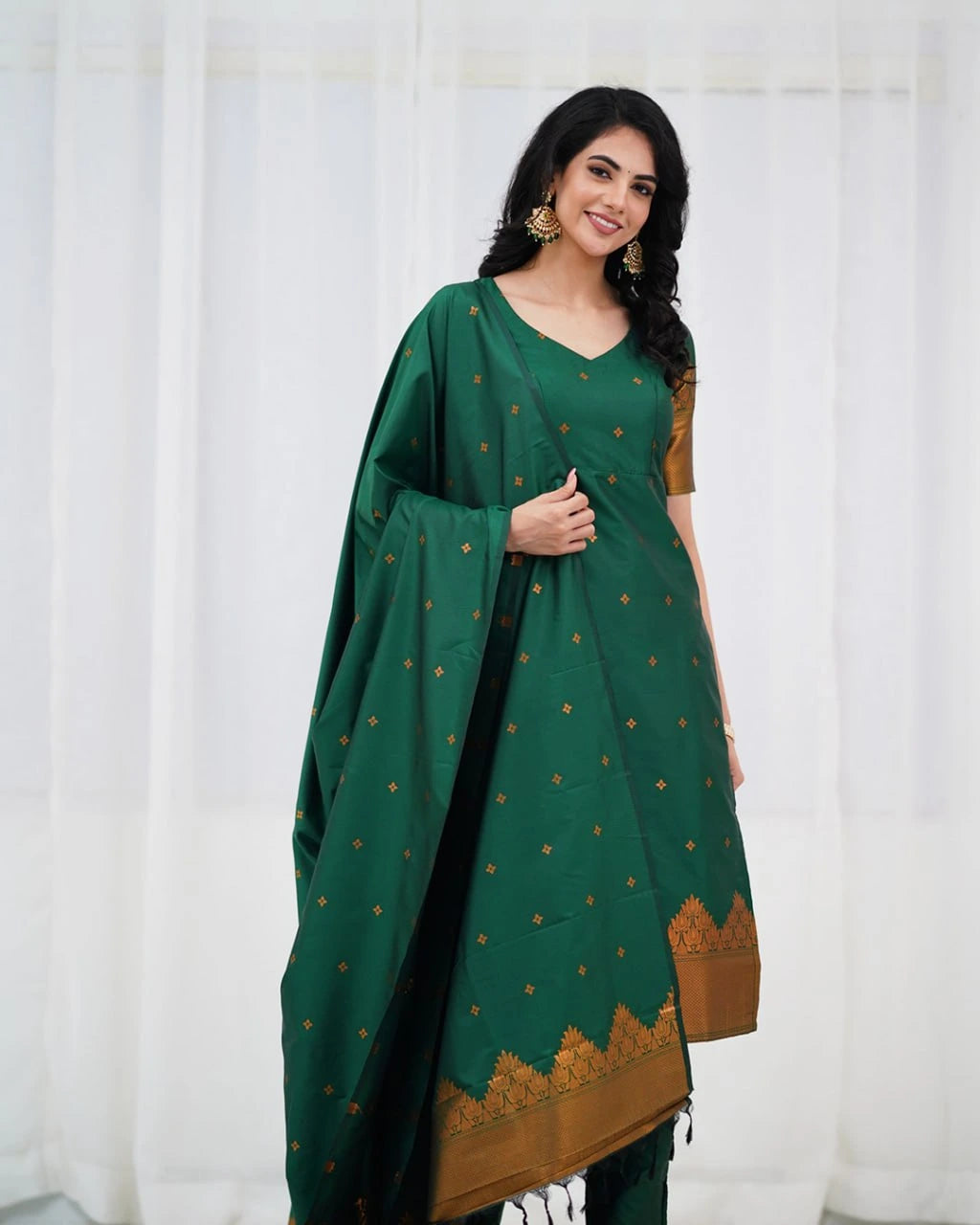 Woman wearing a green and brown traditional outfit with a white curtain background