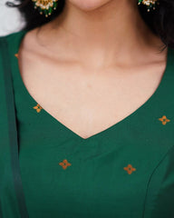 Green top with floral patterns on a person wearing earrings.