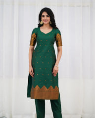 Woman wearing a green traditional outfit with gold patterns against a white background