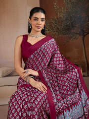 Woman wearing a maroon saree with white patterns indoors.