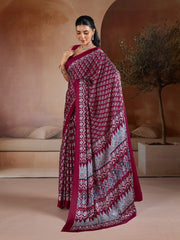 Woman wearing a maroon saree with white patterns in an indoor setting